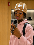 tan knit beanie with a white maple leaf embroidered on the front and the word "CANADA" knitted below it.
