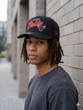 New Era 9FORTY snapback hat features a black crown and a prominent embroidered red script for the Chicago Bulls
