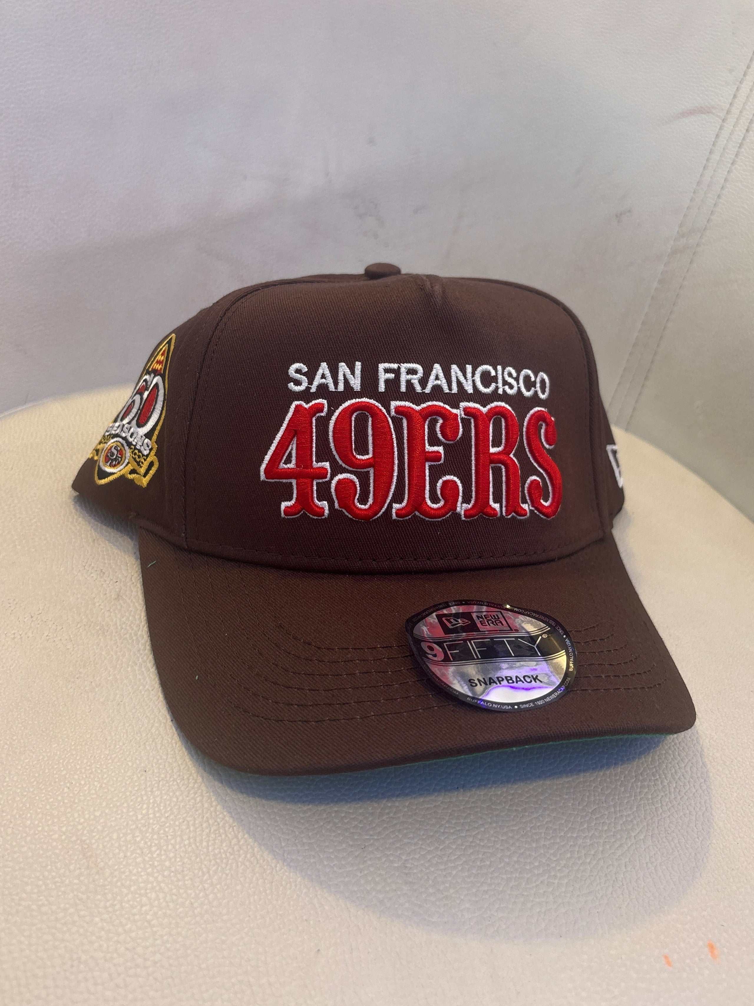 New Era 9FIFTY snapback cap features a prominently embroidered "SAN FRANCISCO 49ERS" logo on the front and a special anniversary side patch