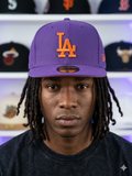 New Era Los Angeles Dodgers 59FIFTY fitted hat features a distinct purple color scheme with vibrant orange embroidery.