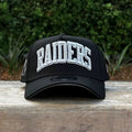 New Era 9FORTY A-Frame cap features a black design with a prominent arched "RAIDERS" script embroidery