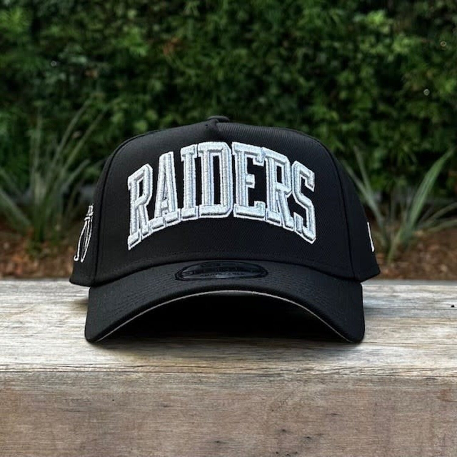 New Era 9FORTY A-Frame cap features a black design with a prominent arched "RAIDERS" script embroidery