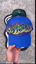 blue Godspeed Neo Trucker Hat features a prominent, multicolored embroidered logo.