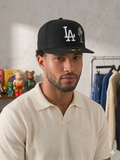 black New Era Los Angeles Dodgers 59FIFTY fitted hat features a white embroidered "LA" logo and a contrasting palm tree graphic.