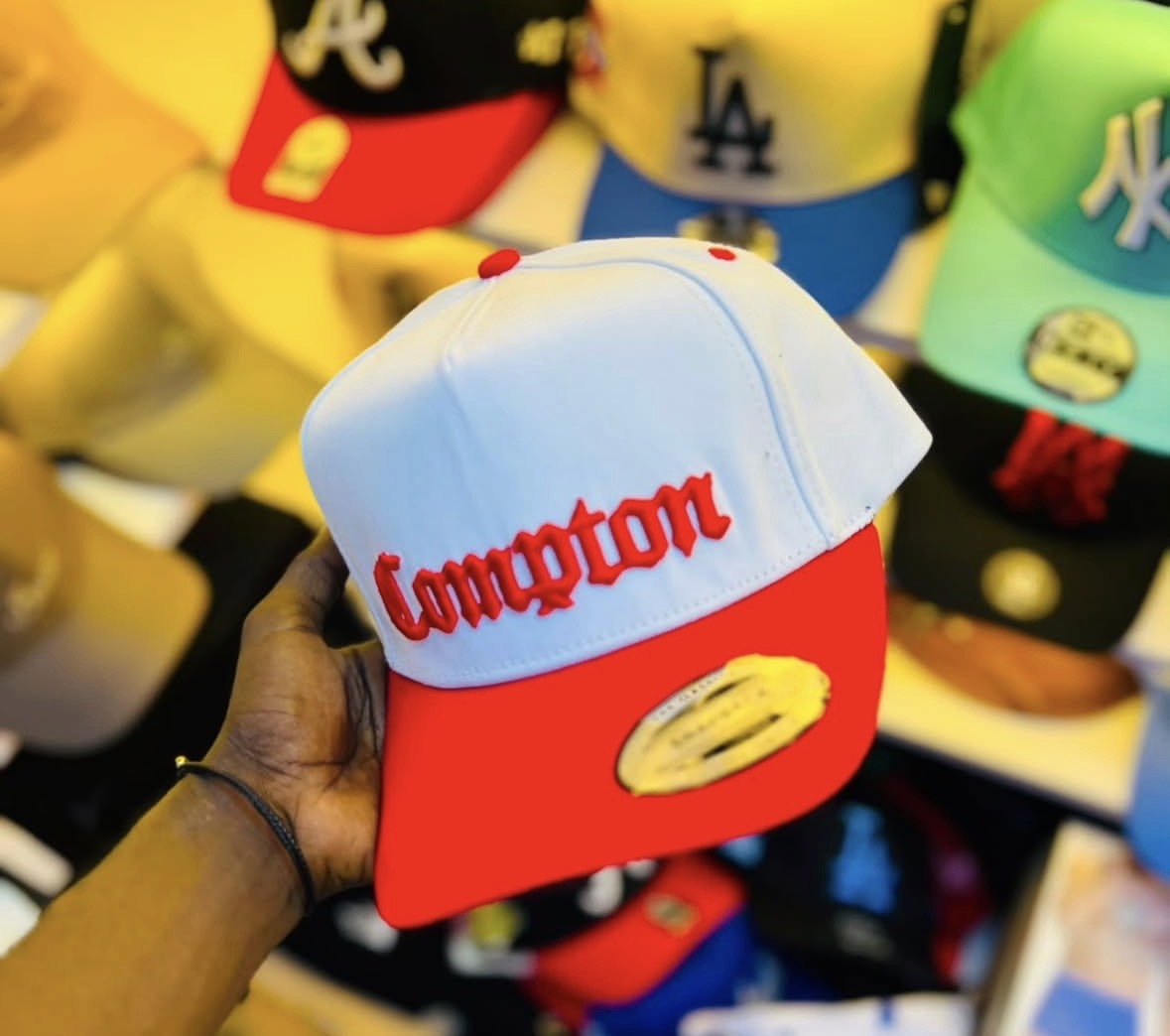 red flatbill snapback hat features prominent red "Compton" embroidery in an Old English font.