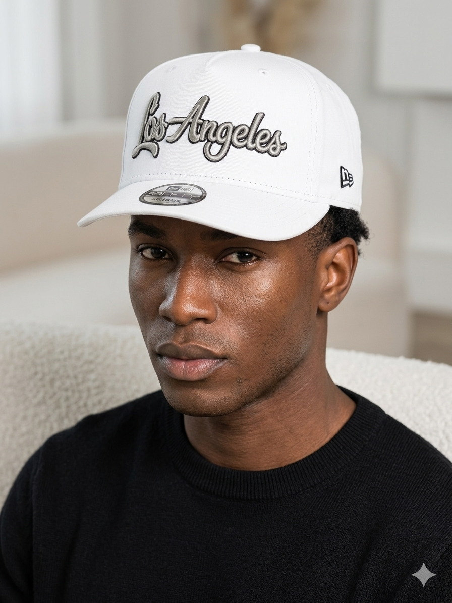 white New Era 9FORTY A-Frame cap features a black and silver chainstitch "Los Angeles" script embroidery on the front.