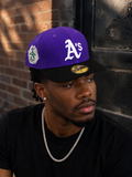 New Era 59FIFTY fitted hat features a distinct purple crown and black brim with a prominent embroidered white Oakland Athletics logo.