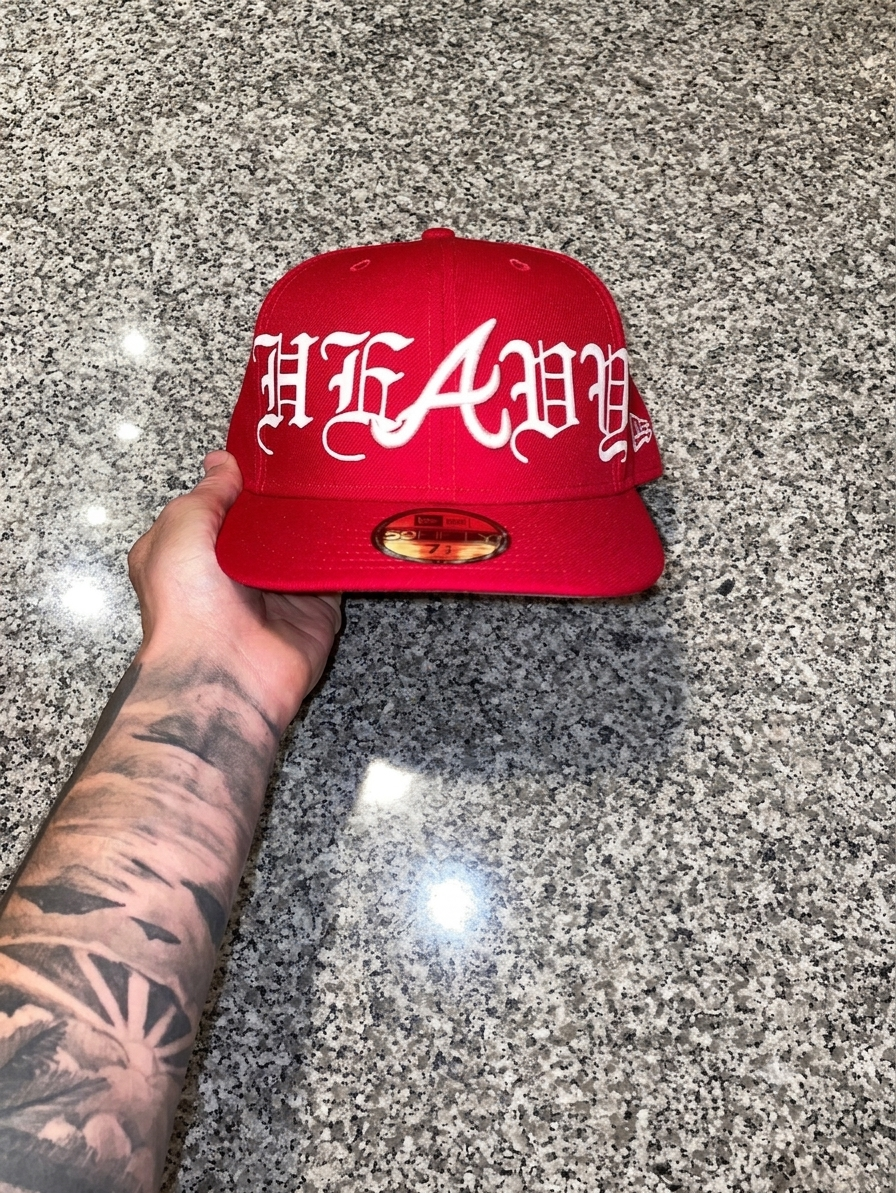 New Era 9FIFTY snapback cap featuring a red crown and white embroidered "Heavy" gothic script.